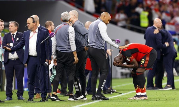 El técnico asistente de Bélgica, Thierry Henry, trata de consolar al delantero Romelu Lukaku.