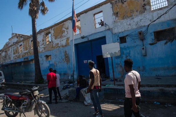 Personas caminan frente a la prisión nacional que está abierta luego de los ataque por parte de bandas armadas, este domingo en Puerto Príncipe (Haití).