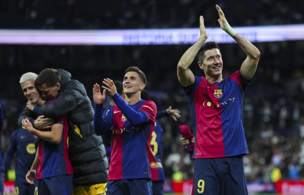 El delantero del FC Barcelona Robert Lewandowski (d) celebra la victoria tras el partido de la jornada 11 de LaLiga EA Sports entre el Real Madrid y el FC Barcelona, este sábado en el estadio Santiago Bernabéu, en Madrid. EFE/Kiko Huesca