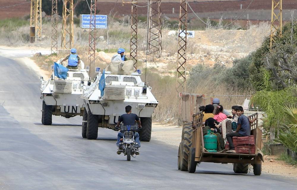 Fotografía de archivo de refugiados sirios que viajan en un tractor cerca de los vehículos de la Fuerza Provisional de las Naciones Unidas para el Líbano (UNIFIL, por su sigla en inglés) cuando abandonan la aldea de Wazzani, en el sur del Líbano, el 15 de septiembre de 2024.