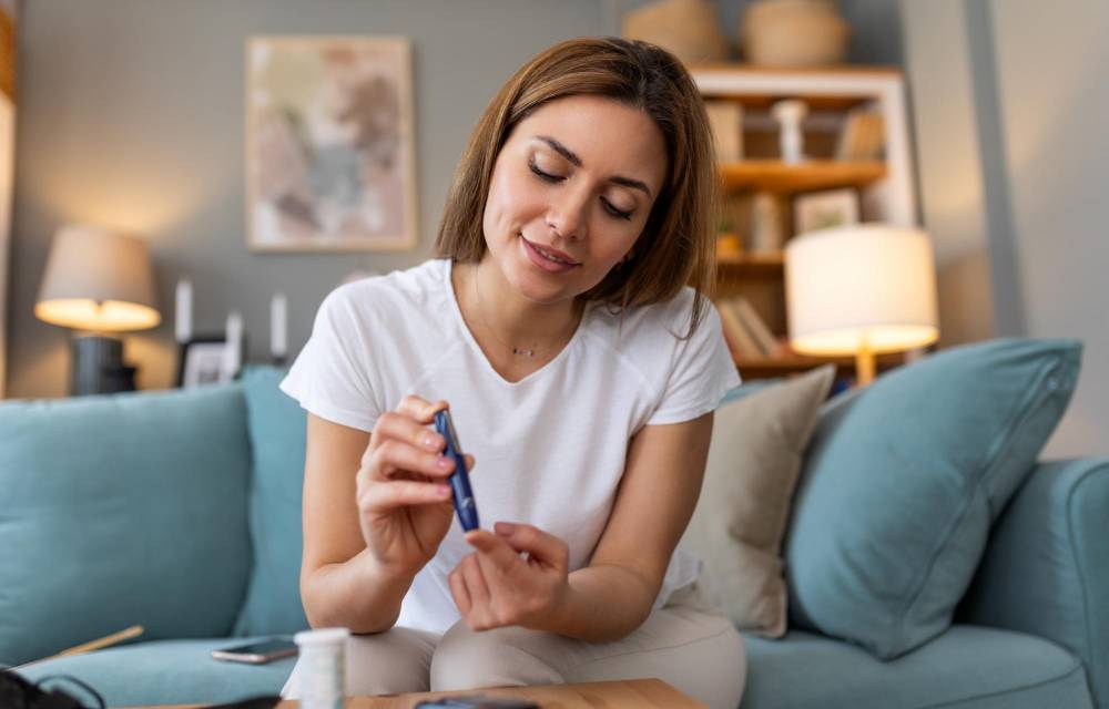 Blood sugar testing at home. Checking Blood Sugar Level At Home. Diabetic Checking Blood Sugar Levels. Woman checking blood sugar level by glucometer and test stripe at home