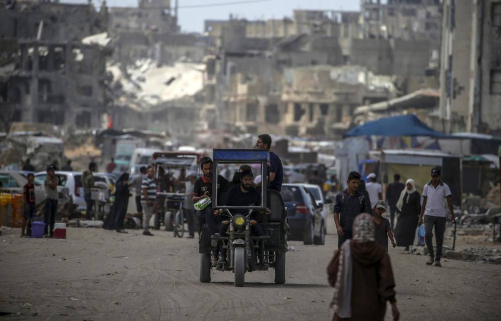 Palestinos caminan entre los edificios destruidos en Jan Yunis.