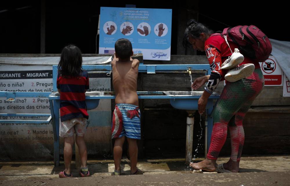 Una mujer y dos niños migrantes tras cruzar la selva del Darién en Lajas Blancas (Panamá).