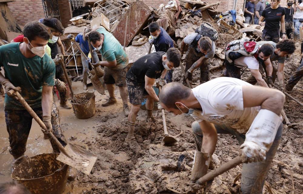 Varias personas retiran el lodo acumulado en una calle de la localidad valenciana de Paiporta, este sábado. Por tercer día consecutivo una marea de voluntarios ha llegado este sábado a barrios del sur de la ciudad de València y a los pueblos de la comarca vecina de l’Horta Sud asolados por la dana para luchar contra un fango, donde grupos especializados de los equipos de intervención buscan cadáveres en garajes o fosos aún anegados.EFE/ Biel Alino