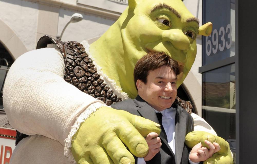 Fotografía de archivo del 20 de mayo de 2010 de una caracterización de Shrek (atrás), la estrella de la famosa saga homónima, y el actor que le de la voz, Mike Myers (frente), mientras reciben la estrella número 2.408 en el paseo de la fama de Hollywood con el nombre del icónico personaje animado, en Hollywood, California (EEUU). EFE/Paul Buck