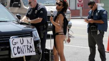 Un artista callejero baila y sostiene un cartel que dice Control de armas.