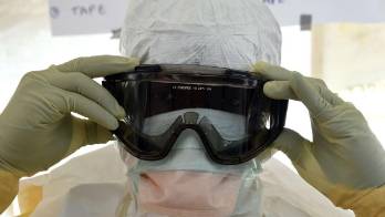 Un trabajador de la salud se pone un traje protector.