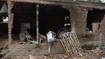 Una mujer entra a su casa afectada por una explosión este jueves, en Robles, Jamundí (Colombia).