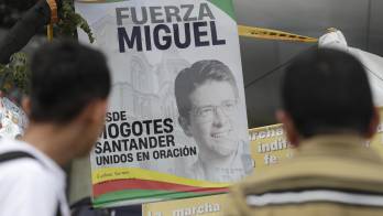 Fotografía de personas orando en un altar improvisado frente a la Fundación Santa Fe, lugar donde permanece hospitalizado el senador colombiano Miguel Uribe Turbay.