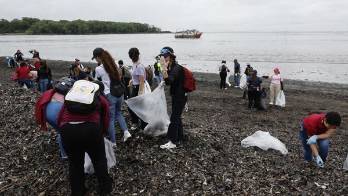 Personas recogen basura durante una jornada de limpieza de playas este sábado, en la desembocadura del Río Juan Díaz, en Ciudad de Panamá (Panamá).