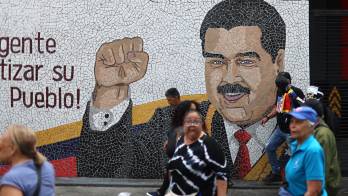 Personas caminan frente a un mural con la imagen del presidente Nicolás Maduro durante una protesta por el salario y las pensiones este jueves, en Caracas (Venezuela). EFE/ Miguel Gutiérrez