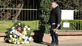 Una persona camina llevando un ramo de flores frente al cementerio privado El Prado este domingo en Rosario (Argentina).