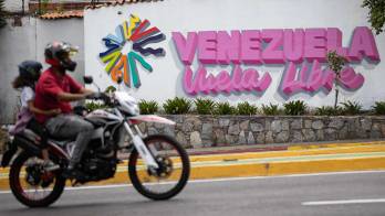 Fotografía del 31 de mayo del 2026 que muestra a personas transitando en motocicleta frente a un mural de Venezuela Libre, en Caracas (Venezuela).