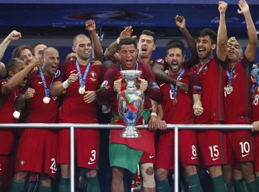 El capitán portugués Cristiano Ronaldo levanta el trofeo flanqueado por sus compañeros de equipo después de ganar la UEFA EURO 2016 partido final entre Portugal y Francia en el Stade de France en Saint-Denis, Francia.