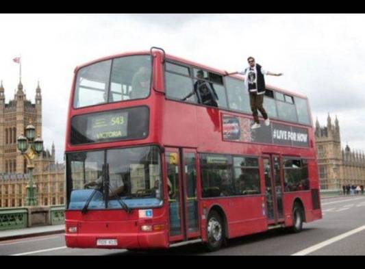 Joven levita en el lateral de un bus