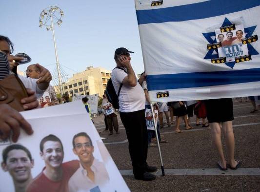 Israelíes sostienen banderas y pancartas con la foto de los adolescentes desaparecidos.