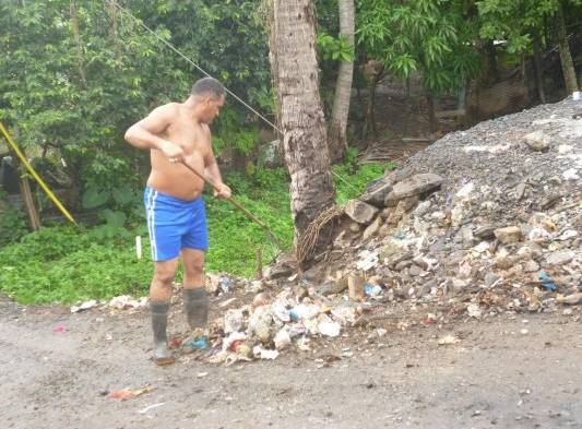 Un residente del área limpia la vereda.