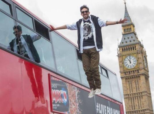 Joven levita en el lateral de un bus