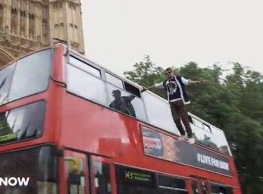 Joven levita en el lateral de un bus