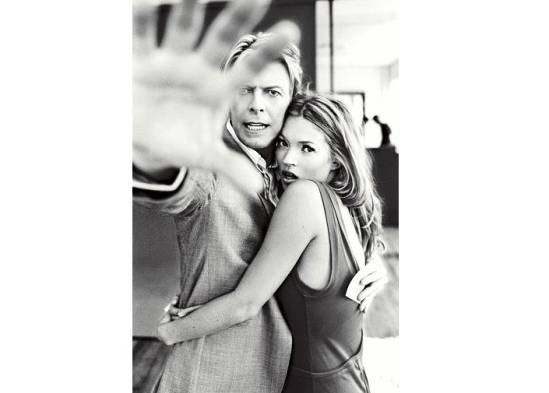 David Bowie abrazando a Kate Moss e intentando tapar el objetivo de la cámara.