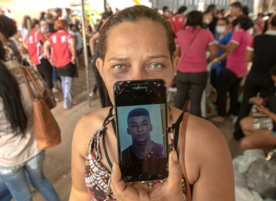 Una mujer muestra una fotografía mientras espera junto a otras personas la entrega de los cuerpos de las víctimas.