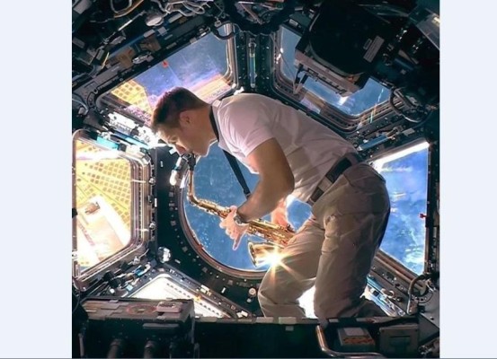 Astronauta tocando sax en la estación espacial europea durante el acto de bienvenida de los próximos juegos de verano.