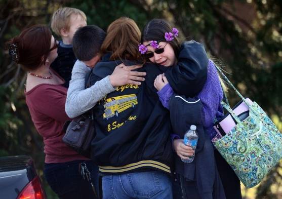 Padres y estudiantes se abrazan junto a School Road, cerca de Franklin High School (secundaria regional), después de que más de una docena de estudiantes fueron apuñalados.