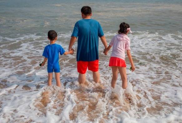 Un padre con sus dos hijos en una playa de Dalian, en el noreste de China.