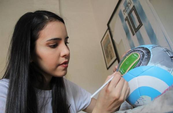 La artista paraguaya Lili Cantero trabajando una de sus obras sobre un balón.