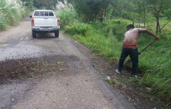 Transportistas se bajan de los buses para echarle tierra a los huecos y poder transitar.