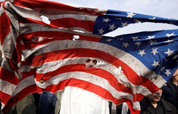 Un manifestante rompe una bandera estadounidense durante una manifestación en Teherán (Irán).