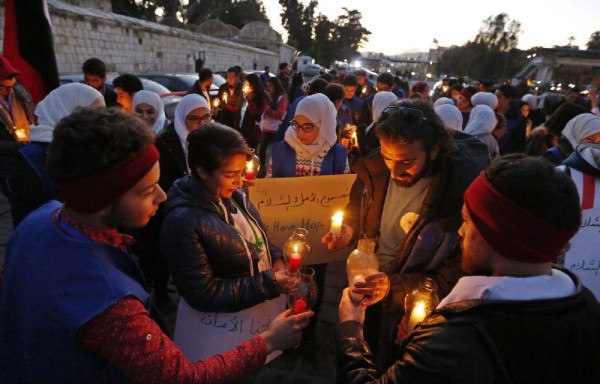 Sirios llevan carteles que dicen ‘queremos la paz', durante una vigilia en la Plaza Ummayyad, en Damasco.