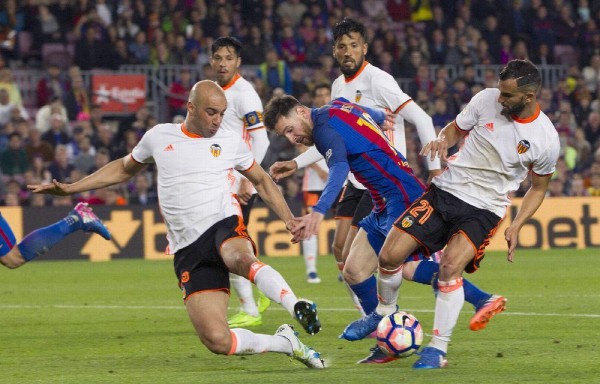 Messi (c) lucha el balón con el tunecino Aymen Abdennour (i) y Martín Montoya (d), del Valencia CF.