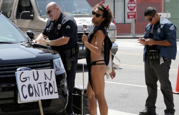 Un artista callejero baila y sostiene un cartel que dice Control de armas.