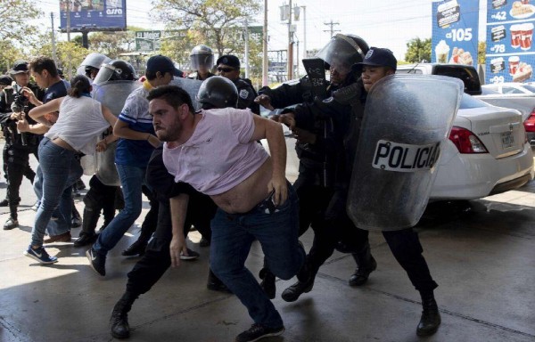 Agentes intentando detener al reportero gráfico Luis Sequeira.