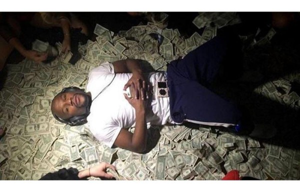 Mayweather, acostado sobre cientos de dólares mientras mujeres colocan los billetes a su alrededor.