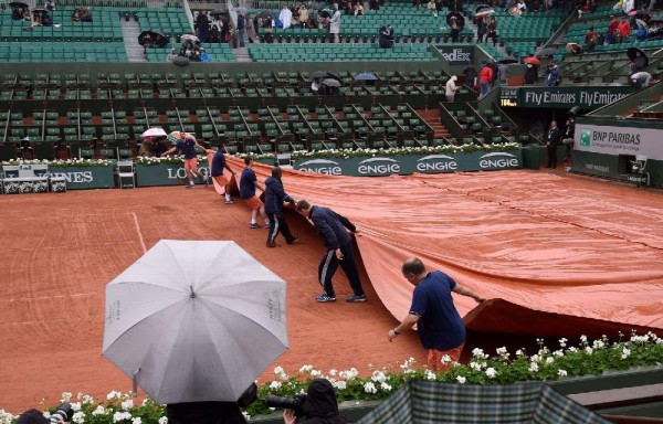 Los trabajadores colocan una carpa a la cancha de arcilla.