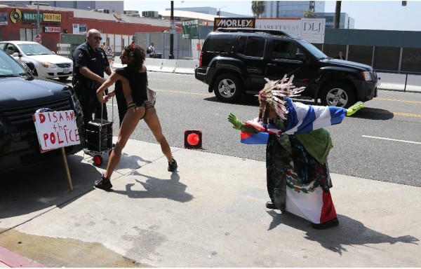 Artista callejero baila y sostiene un cartel que dice Control de armas.