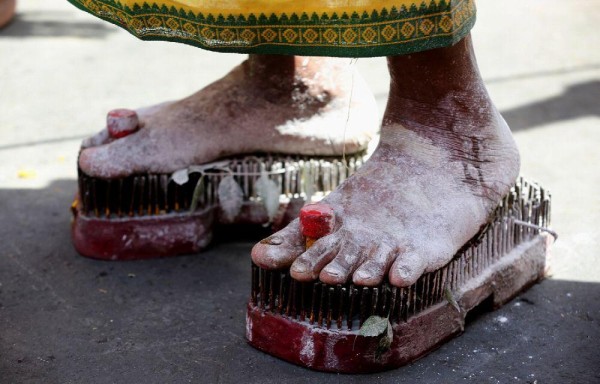 CELEBRACIÓN | Un devoto indio de la comunidad Tamil camina con un calzado de clavos de hierro en una procesión durante el festival Mariamman, este miércoles en Bhopal, India. Feligreses participan descalzos en una procesión como parte del ritual anual para apaciguar a la diosa Kali por el bienestar de sus familias. También hubo participantes que se perforaron con ganchos la espalda como parte del ritual.