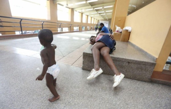 El sueño vence a emigrantes en Albrook, mientras un bebé se entretiene caminando.