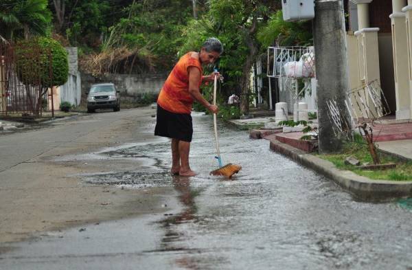 Residentes tienen que limpiar con escoba la basura que está en la vía.
