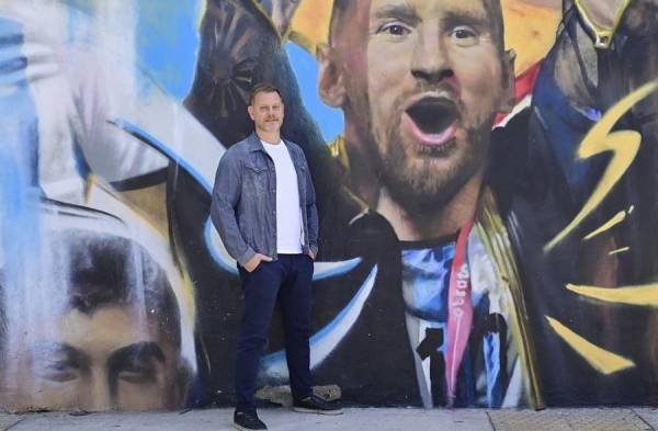 El periodista Sebastián Fest posa junto a una pintura de Lionel Messi, en Buenos Aires.