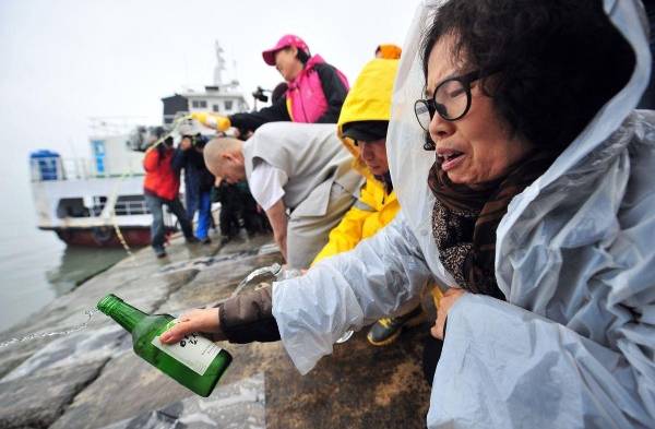 Pariente rocía alcohol mientras se reza por los pasajeros que aún no se encuentran.