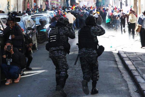 Policías avanzan durante un enfrentamiento con simpatizantes del expresidente de Bolivia Evo Morales (2006-2019) este miércoles, en La Paz (Bolivia).