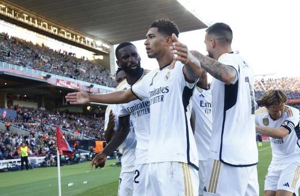 El delantero inglés del Real Madrid Jude Bellingham (c) celebra su gol, segundo de su equipo, y que da la victoria al conjunto blanco, durante el partido de LaLiga que enfrentó al FC Barcelona y al Real Madrid en el Estadio Olímpico Lluís Companys de Barcelona.