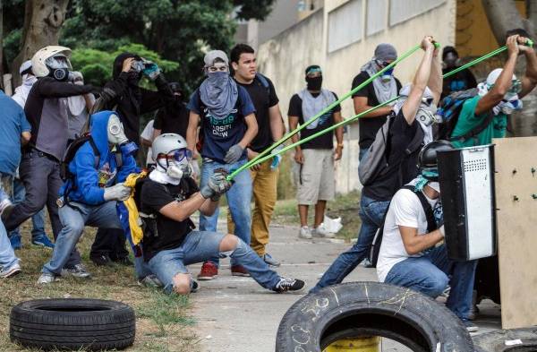 Manifestantes participan en un enfrentamiento con elementos de la Policía Nacional Bolivariana (PNB), durante una protesta en Terrazas del Avila, en Caracas, Venezuela.