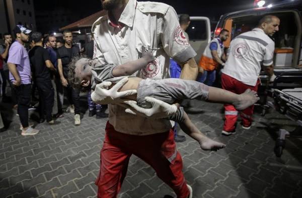 Un miembro de la Media Luna Roja Palestina (MLPR) lleva a un niño herido en la ciudad de Gaza.