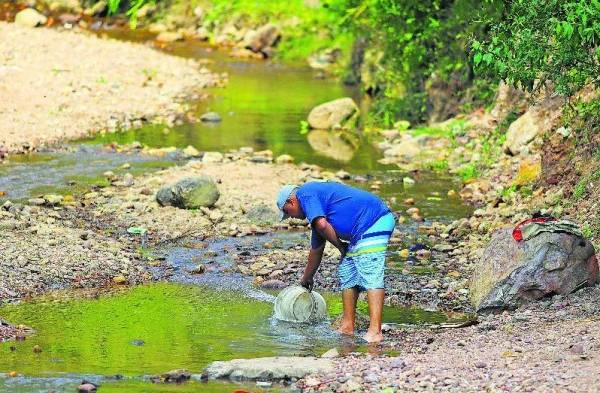 Un hombre recoge agua para combatir el calor.