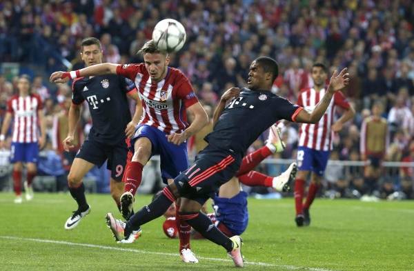 El centrocampista brasileño del Bayern de Múnich Douglas Costa (d) lucha el balón con Saúl Ñíguez, del Atlético de Madrid, durante el partido de ida de semifinales de la Liga de Campeones que se disputa esta noche en el estadio Vicente Calderón, en Madrid.