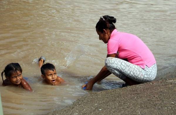 Niños hondureños víctimas de Eta e Iota se bañan en pestilentes aguas estancadas